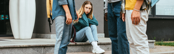 Récolte horizontale de fille triste regardant des adolescents multiethniques à l'extérieur - Photo, image