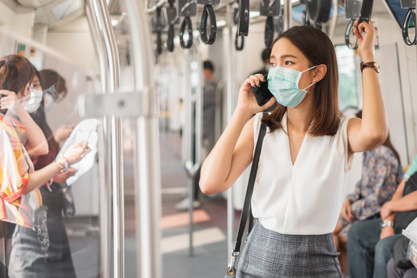Coronavirus(Covid-19) concept, Asian woman wearing protective face mask to protect infection from coronavirus covid-19 standing at sky train and crowd people - Фото, зображення