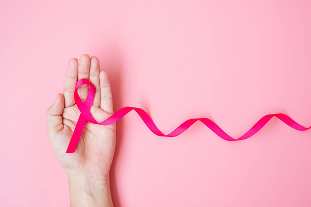 Říjen Rakovina prsu Vědomost měsíc, dospělý Žena ruka drží Růžová stuha na růžovém pozadí pro podporu lidí žijících a nemocí. Koncept Mezinárodního dne žen, matek a světového dne rakoviny - Fotografie, Obrázek