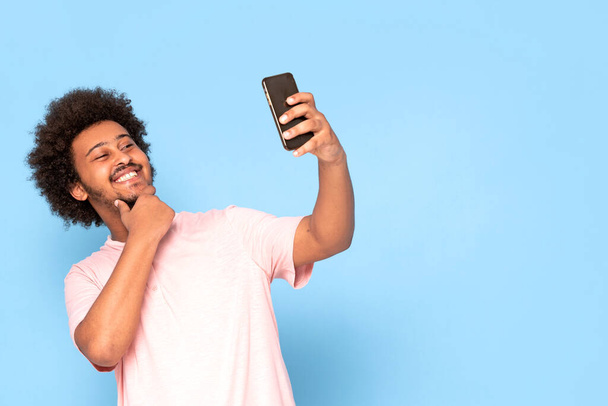 Cheerful young african guy in casual t-shirt holding mobile phone , smiling. - Foto, afbeelding