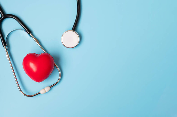 Bovenaanzicht Stethoscoop met rode hartvorm op blauwe achtergrond met kopieerruimte voor tekst. Gezondheidszorg, levensverzekering, Gezondheidsdag, Wereldhartdag en Happy Doctor Day concept - Foto, afbeelding