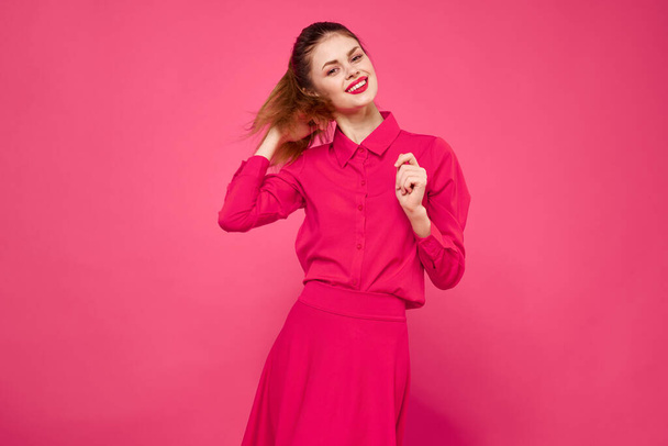 Retrato de una mujer pelirroja vestida con ropa brillante sobre un fondo rosa recortada vista de gesto con las manos - Foto, Imagen