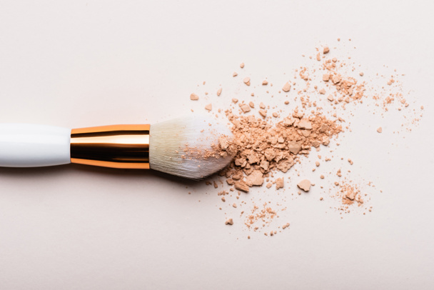 top view of cosmetic brush with face powder on beige background - Φωτογραφία, εικόνα
