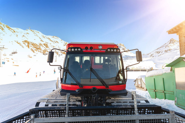 Red modern snowcat ratrack with snowplow snow grooming machine preparing ski slope piste hill at alpine ski winter resort Ischgl in Austria. Βαρέα μηχανήματα οχημάτων τροχιάς εξοπλισμού βουνού - Φωτογραφία, εικόνα