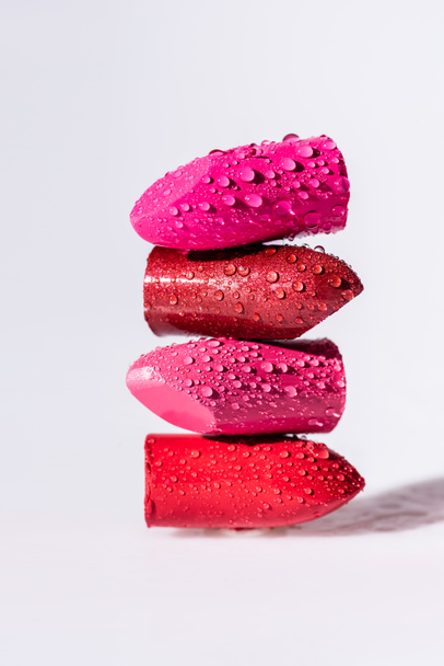 close up view of wet colorful lipsticks on white background - Foto, Bild