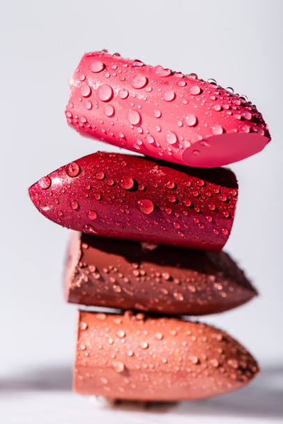 close up view of wet colorful lipsticks on white background - Photo, Image
