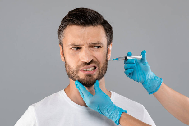 Бородатый мужчина получает инъекцию красоты в салоне - Фото, изображение