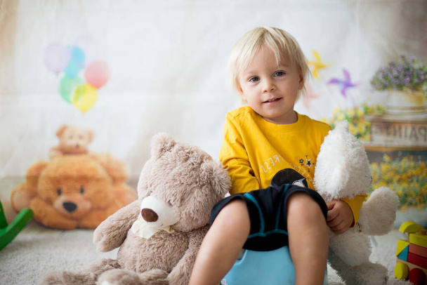 Cute toddler boy, potty training, playing with his teddy bear on potty - Foto, Bild