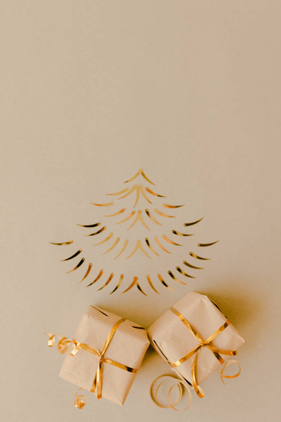 christmas tree made of gold decor on a kraft paper background with two gifts tied with a gold ribbon - Fotoğraf, Görsel