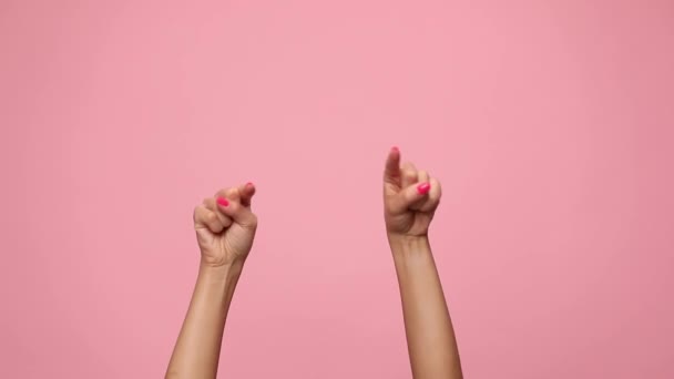 vrouw houdt handen in de lucht, wijzende vingers en dansen op roze achtergrond - Video