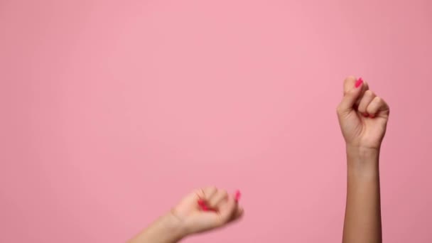 Frau hält Hände in die Luft, tanzt und öffnet Arme, zeigt und präsentiert auf rosa Hintergrund - Filmmaterial, Video