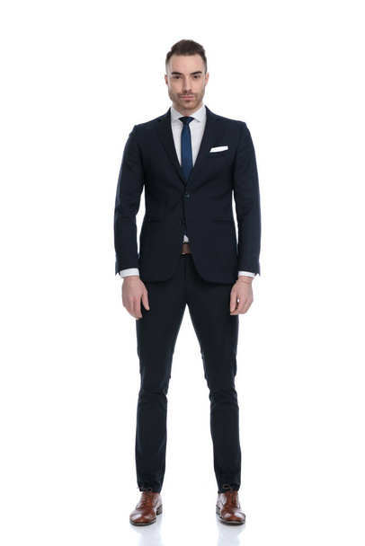 Serious businessman looking forward and wearing suit while standing on white studio background - Zdjęcie, obraz