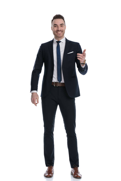 Дружній бізнесмен посміхається і обговорює, жестикулюючи, стоячи на білому фоні студії
 - Фото, зображення