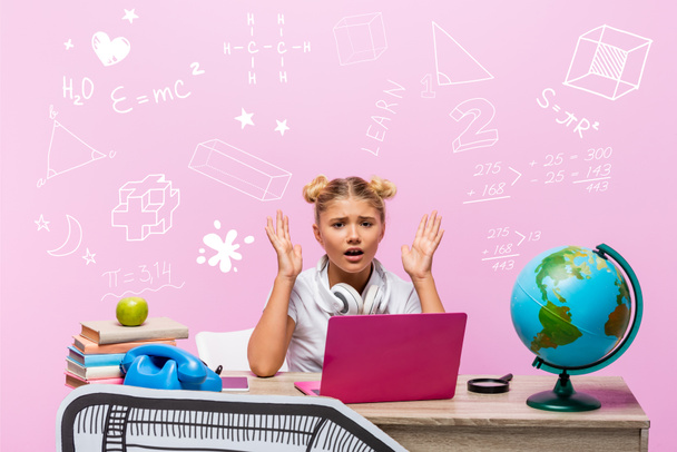 Worried kid looking at camera near laptop, books, paper art, globe, retro telephone and illustration on pink  - Foto, imagen