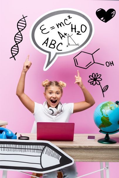 Excited kid pointing with fingers at speech bubble with illustration near laptop, smartphone and globe on pink - Foto, immagini