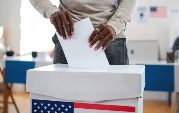 Unrecognizable african-american man putting his vote in the ballot box, usa elections and coronavirus. - Φωτογραφία, εικόνα