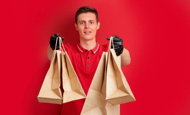handsome caucasian delivery man holding paper bag with takeaway food - Foto, Imagem
