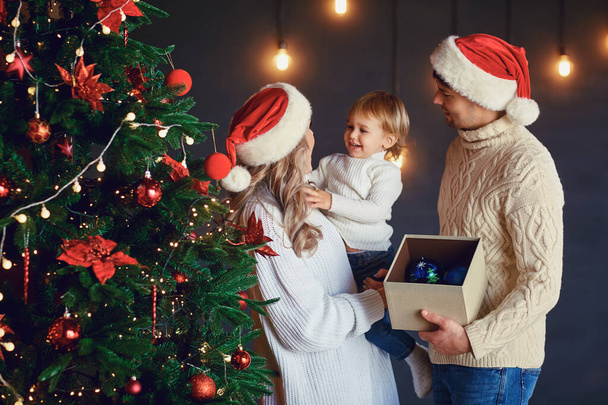 Family decorates the Christmas tree in the room at Christmas - Foto, afbeelding