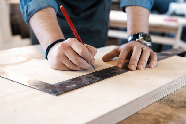 Carpenter working on woodworking machines in carpentry shop. A man works in a carpentry shop. - Foto, imagen