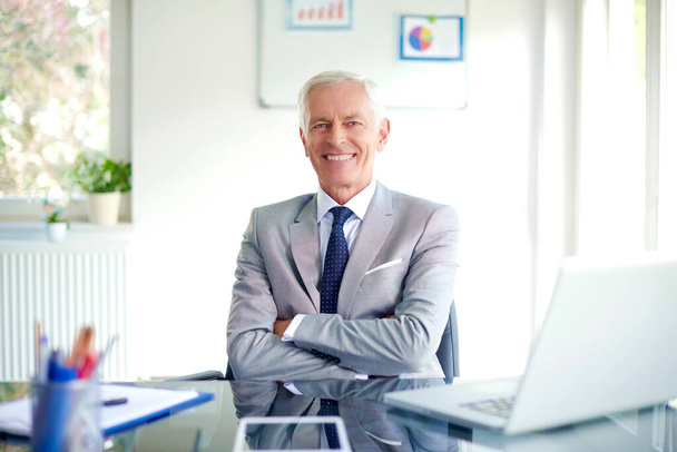 Happy senior businessman sitting with folded arms at office desk in the office. - Fotoğraf, Görsel