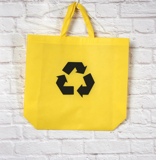 bolsa de viscosa amarilla reutilizable vacía sobre un fondo blanco, concepto de reducción de residuos plásticos - Foto, Imagen