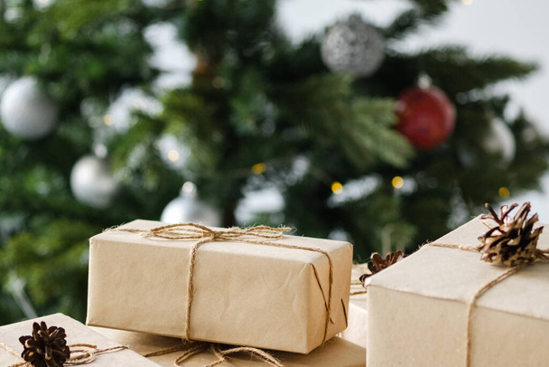 Noel hediyeleri ahşap bir masanın üzerinde süslemeli bir Noel ağacının arka planında. Noel ve Yeni Yıl kavramı. - Fotoğraf, Görsel