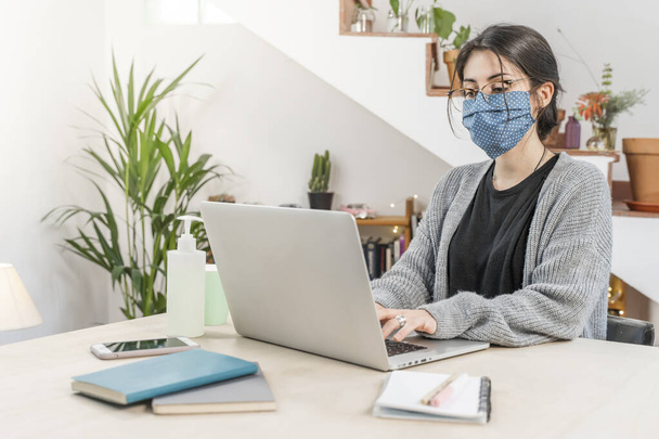 Coronavirus. Young business woman isolated working from home wearing protective mask. Woman in quarantine for coronavirus wearing home made mask. Working from home with sanitizer gel. Quarantine.  - Valokuva, kuva