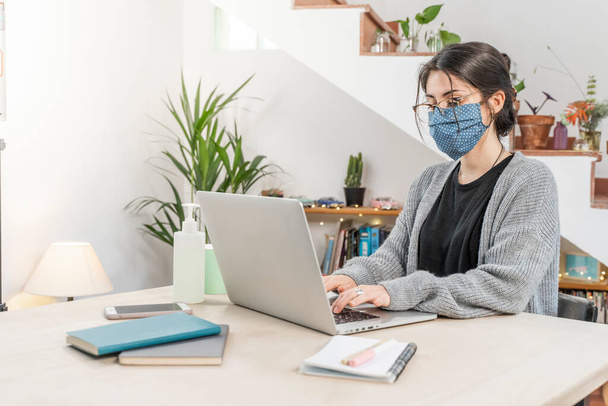 Coronavirus. Young business woman isolated working from home wearing protective mask. Woman in quarantine for coronavirus wearing home made mask. Working from home with sanitizer gel. Quarantine.  - Foto, Bild
