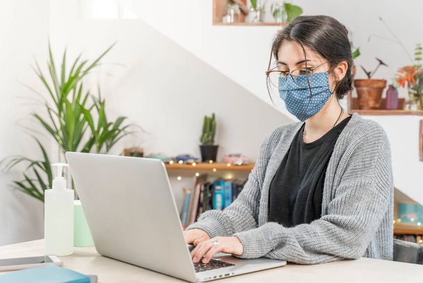 Coronavirus. Young business woman isolated working from home wearing protective mask. Woman in quarantine for coronavirus wearing home made mask. Working from home with sanitizer gel. Quarantine.  - Foto, immagini