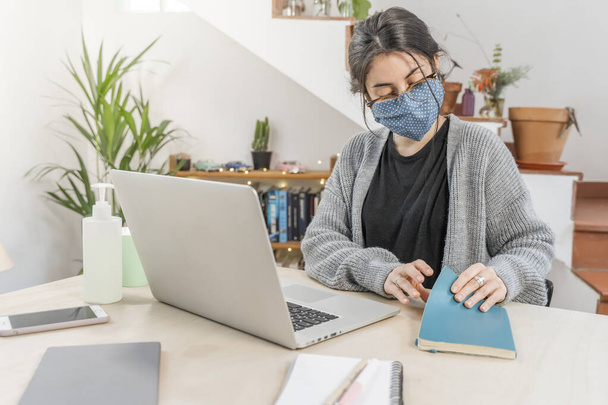 Coronavirus. Young business woman isolated working from home wearing protective mask. Woman in quarantine for coronavirus wearing home made mask. Working from home with sanitizer gel. Quarantine.  - Foto, afbeelding
