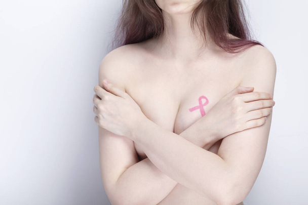 Всемирный день борьбы с раком груди. Женщина накрывает грудь руками розовой лентой. Октябрь месяц осведомленности о раке молочной железы - Фото, изображение