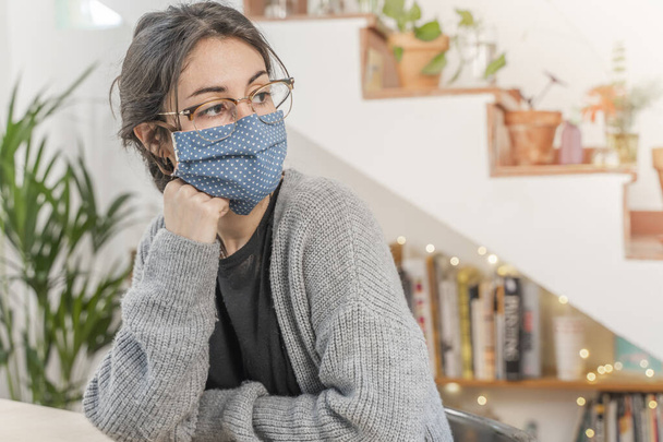 Coronavirus. Young business woman isolated working from home wearing home made protective mask. Woman in quarantine for coronavirus is exhausted and tired. Stay at home. Quarantine. Depressed.  - 写真・画像