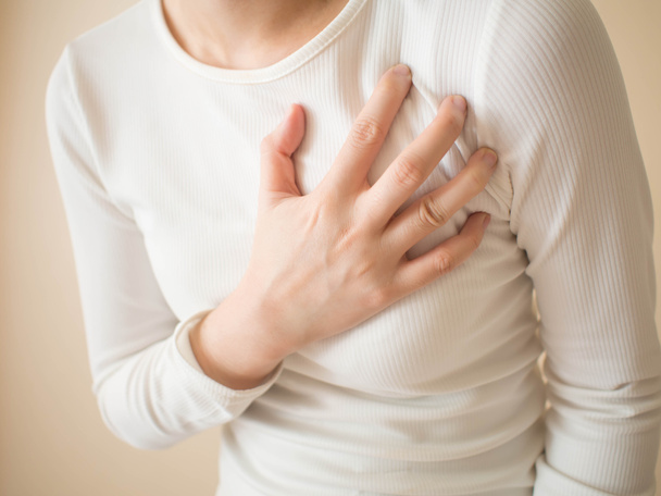 Heart attack/problems. Young female suffering from severe chest pain. Warning signs of unstable angina or myocardrial infarction disease. Health care and cardiological concept. Close up. - Foto, Imagen