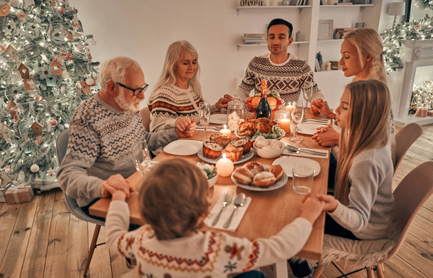 クリスマスのテーブルで祈る家族 - 写真・画像