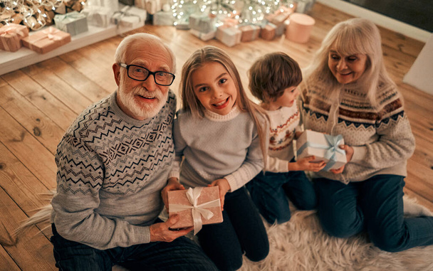 De gelukkige grootouders geven geschenken aan kinderen - Foto, afbeelding