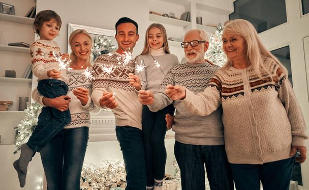 La famille heureuse avec des étincelles debout près de l'arbre de Noël - Photo, image