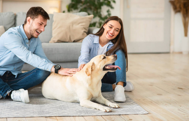 Молодая семья из двух человек сидит на полу с собакой - Фото, изображение