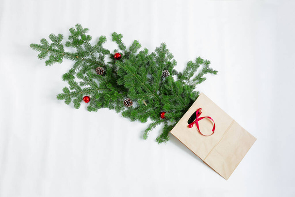 Gałęzie świerkowe z zabawkami noworocznymi i torbą prezentów leżą na białym tle. - Zdjęcie, obraz