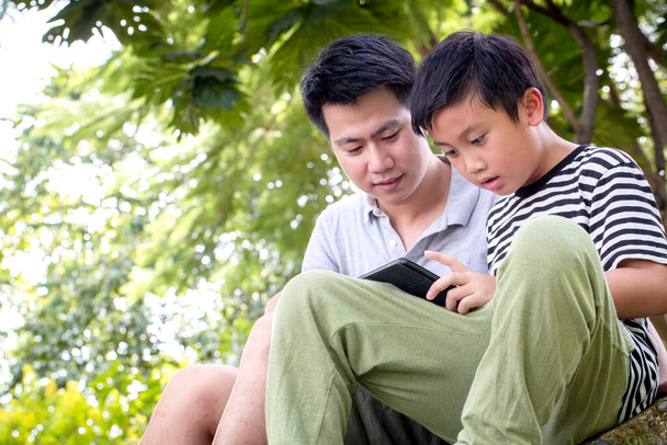 Ojciec i syn korzystający z tabletu i uśmiechnięty szczęśliwy podczas spędzania czasu razem w Patk, Happy koncepcji czasu rodzinnego - Zdjęcie, obraz