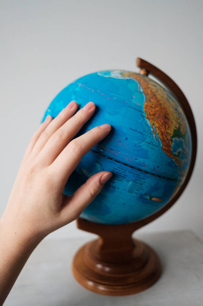 The girl points to a location on the world globe. Chooses a place to travel on the globe. - Photo, Image