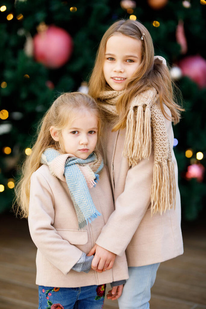 niñas con abrigos cerca de un gran árbol de Navidad - Foto, imagen