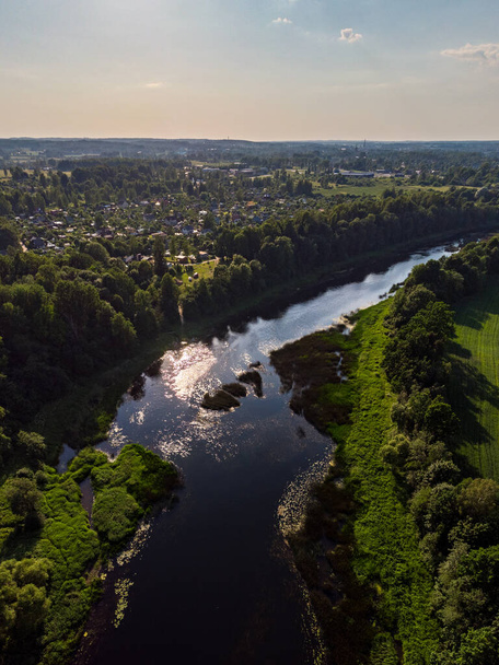 Todellinen maaseutu näkymä o joki Venta virtaa läpi ihanan ympäristön puita lämpimänä kesäpäivänä. Latviassa otettu kuva. - Valokuva, kuva