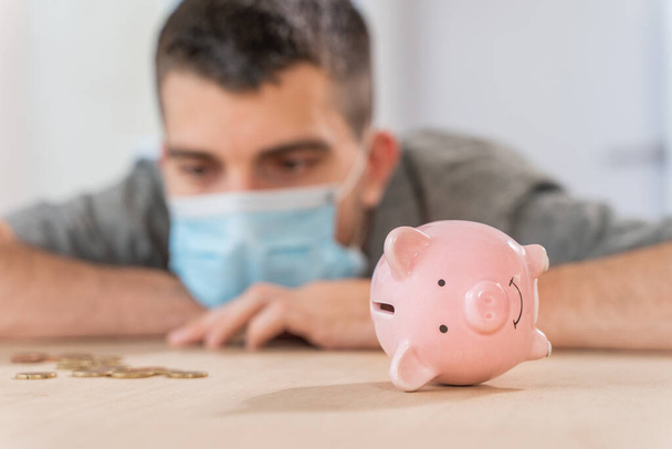Coronavirus. Depressed and worried business man because impact on retail businesses shut down causing unemployment financial distress. Save money. Quarantine. Isolated. Piggy bank.   - Foto, imagen