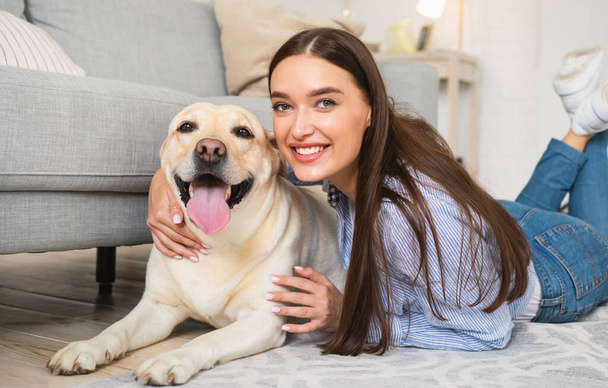 Young happy lady with her labrador lying on floor - Foto, Bild