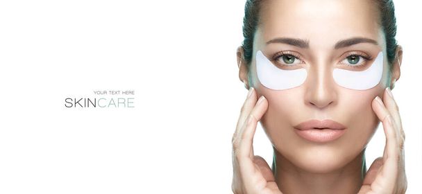 Eye care cosmetic mask. Beautiful woman with healthy fresh skin using patches under eyes. Beauty and eye skin care banner. Eye skin rejuvenation treatment. Isolated on white background with copy space - Photo, Image