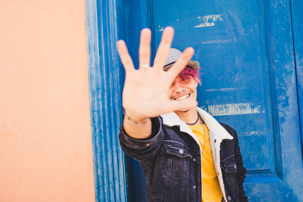 Fröhlicher Teenager lächelt und legt seine Hände auf die Kamera, um das Bild zu stoppen  - Foto, Bild