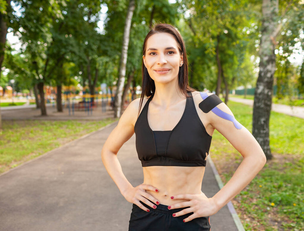 Fit woman with kinesiological taping posing outdoors. - 写真・画像