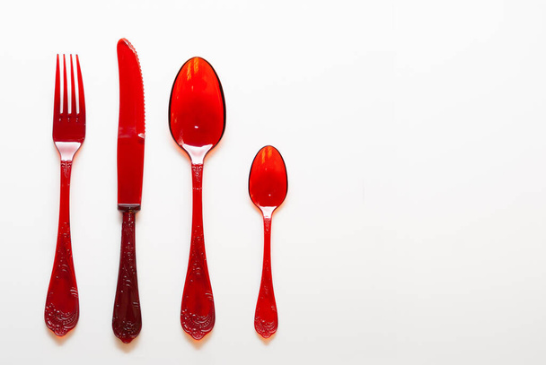 Red plastic cutlery with ornamentation on white background with space for text - Photo, Image