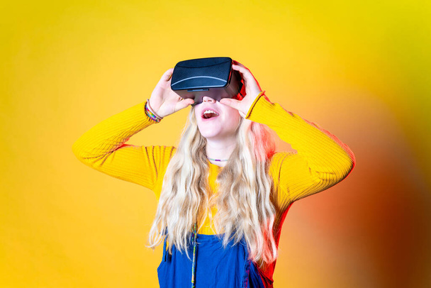 Caucasian woman on green background using vr glasses - Isolated caucasian young woman wearing futuristic headset astonished - entertainment, technology, futuristic concept - Photo, Image