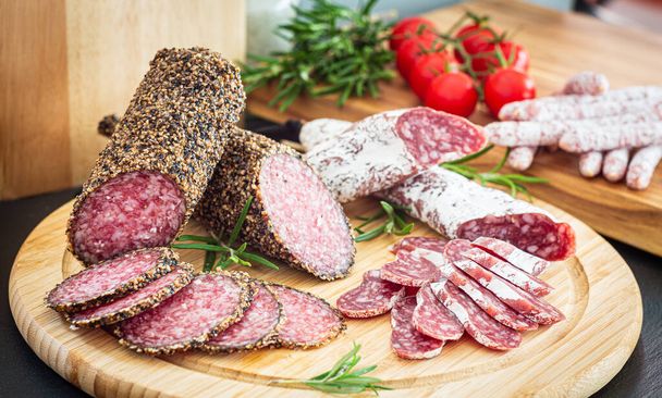 Salame di maiale italiano a fette assortite su piatto di legno - Foto, immagini